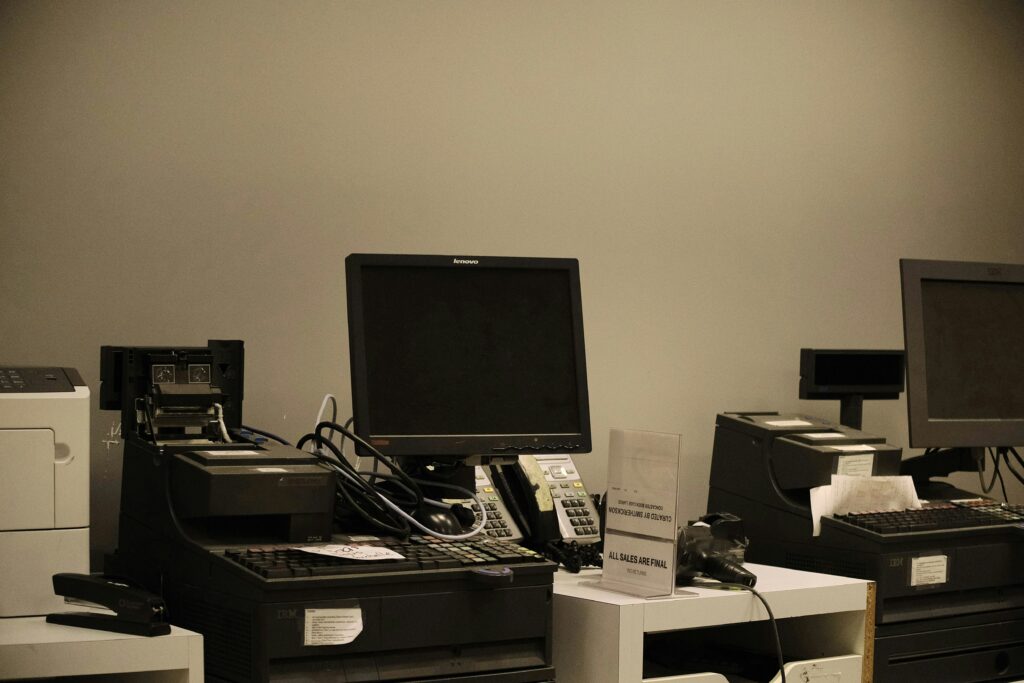 A cluttered office full of junk computers and miscellaneous office equipment and furniture