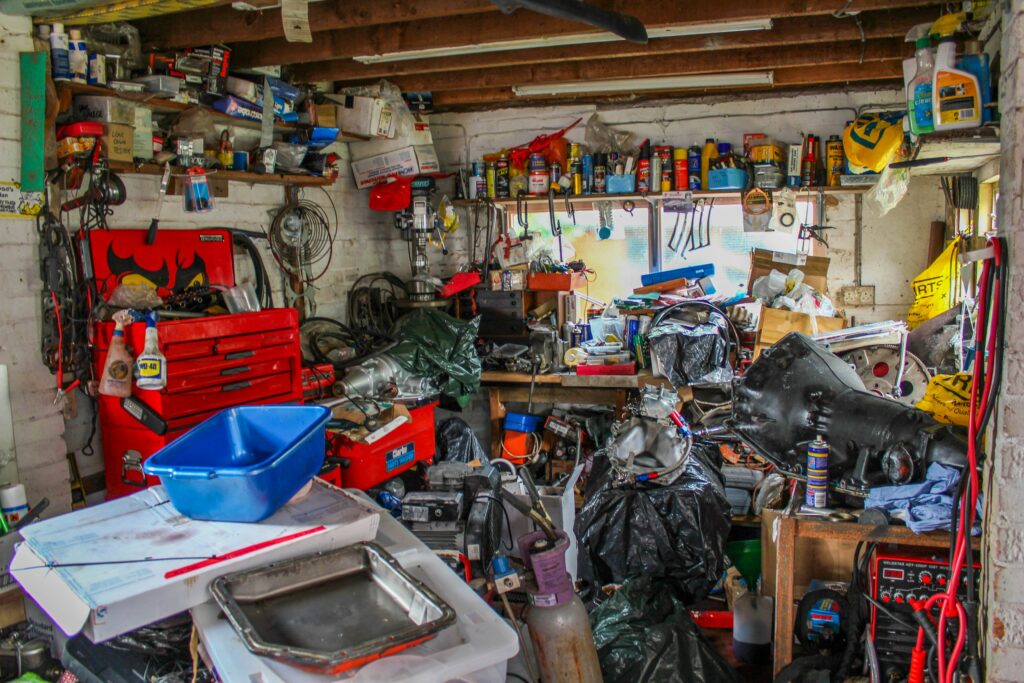 A messy and cluttered garage with various junk piled everywhere