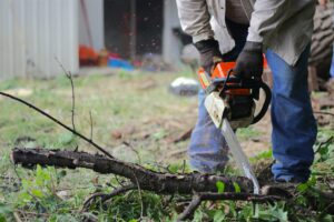 A person cutting up yard debris with a chainsaw